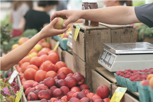 Someone buys an apple at a fruit stand